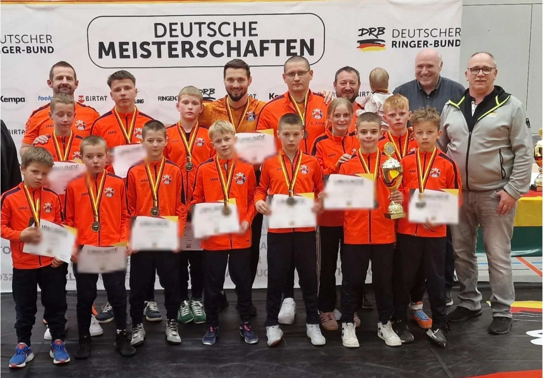Die Schülermannschaft des KSC Olympia Graben-Neudorf mit Medaillen, Urkunden und Pokal vor der Banderole der Deutschen Meisterschaften
