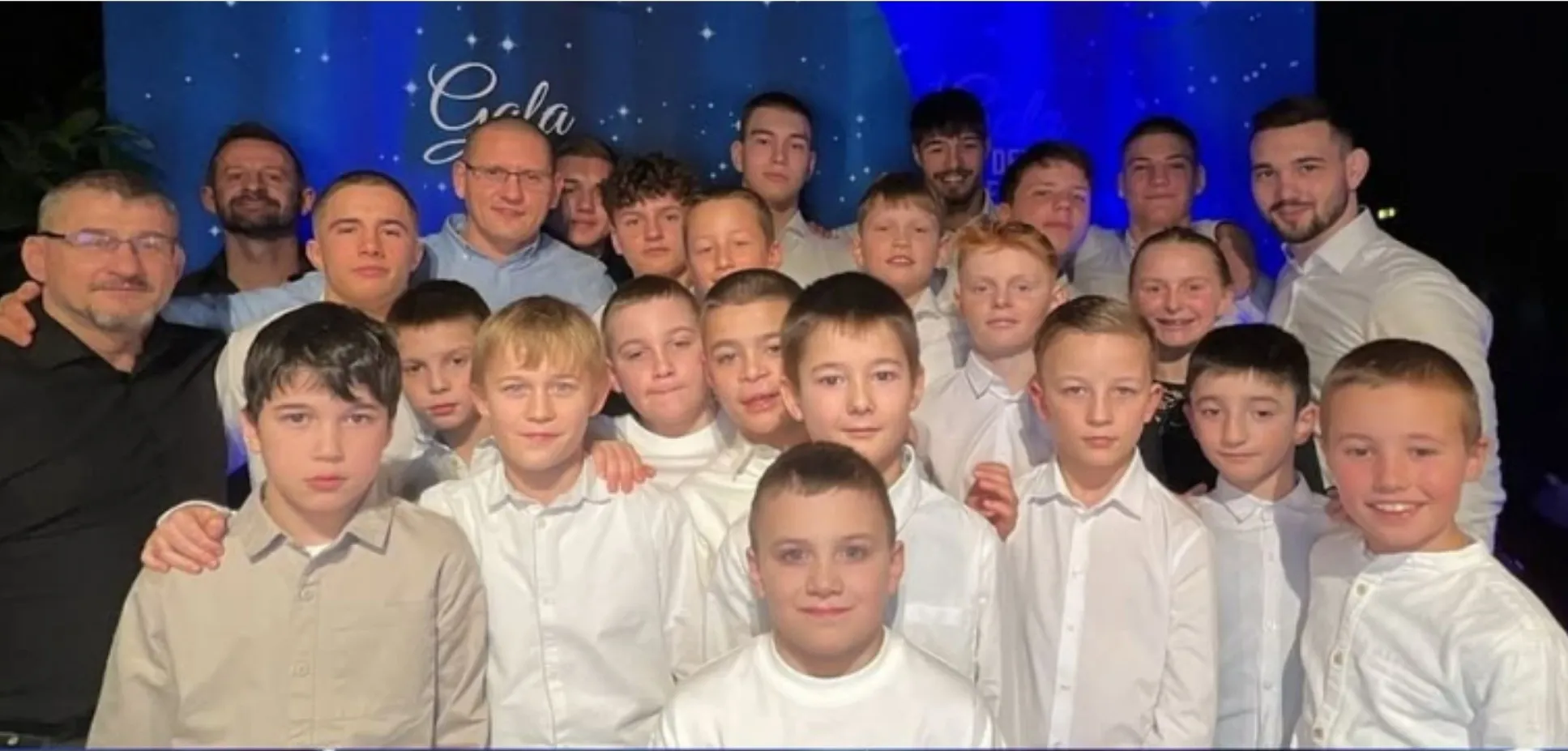 Gruppenbild der Schülermannschaft mit ihren Trainern vor der blauen Bühnenwand der „Gala der Besten“ der Gemeinde