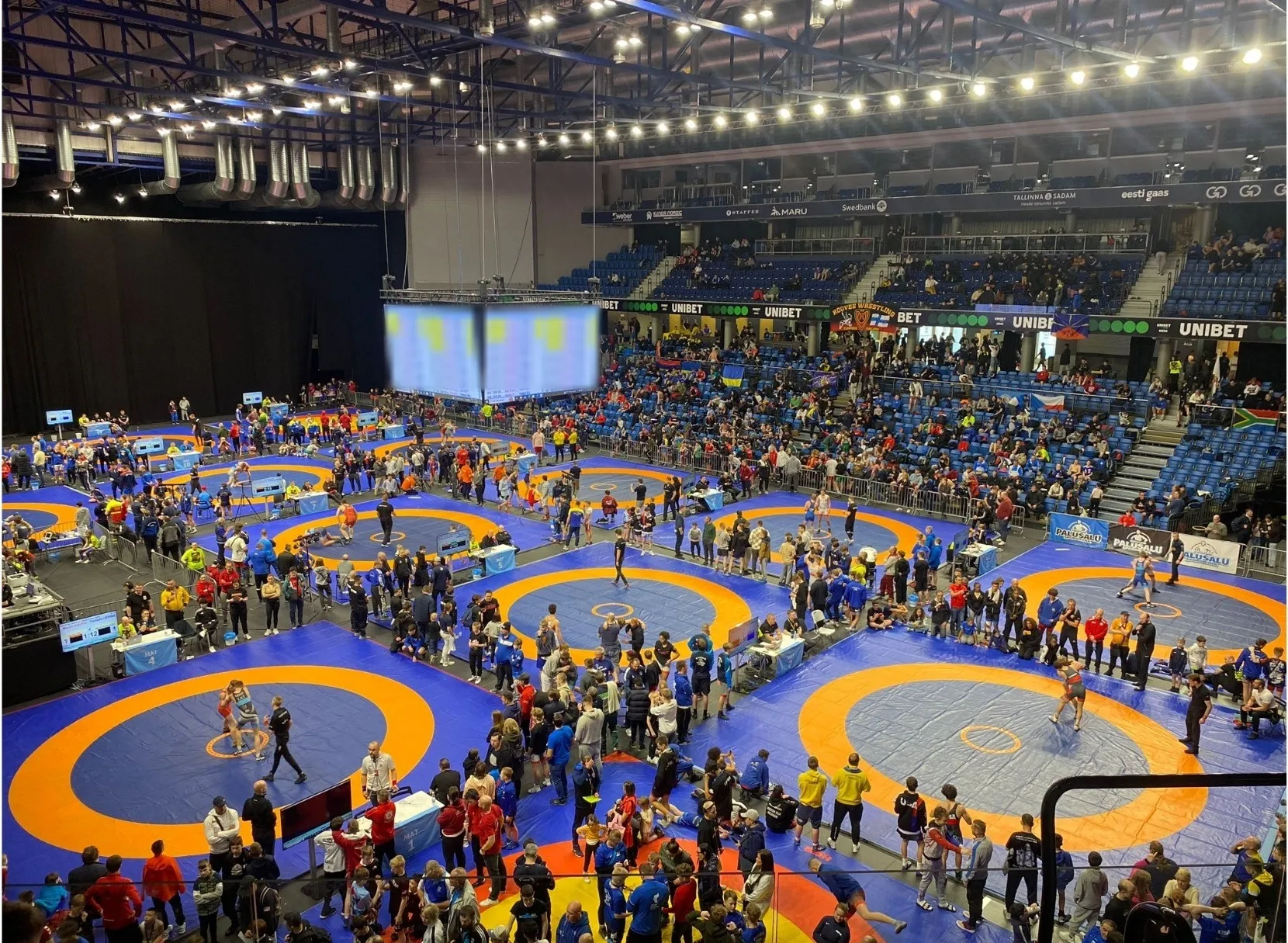 Blick von oben in die Halle des Tallinn Open: sechs blau-orange Ringermatten, dicht besetzte Tribünen